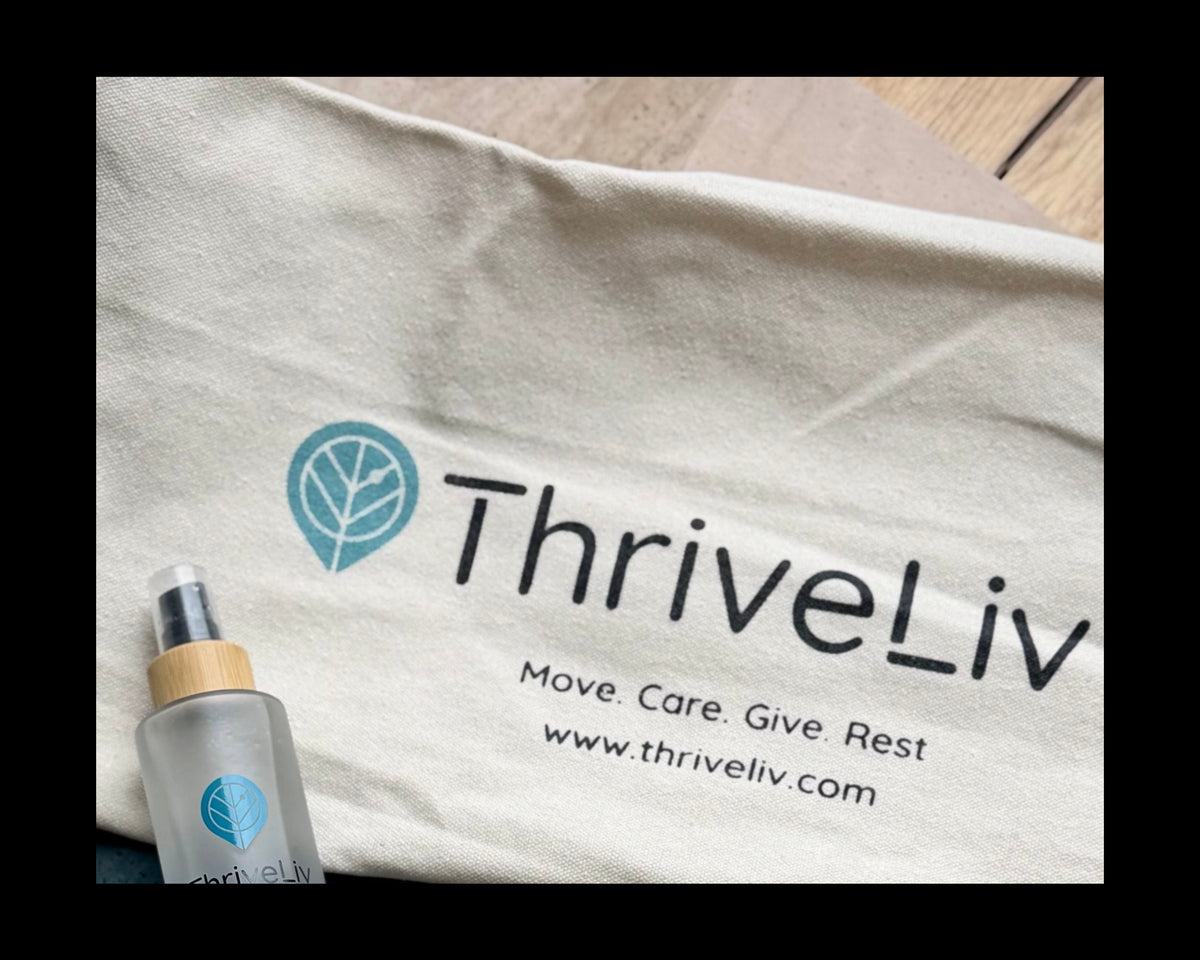 White mat bag with 'ThriveLiv' logo and a bottle of grip spray on a wooden surface.