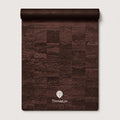 A rolled-up dark brown textured mat or rug with a patchwork wood-grain pattern, featuring the white ThriveLiv logo near the bottom, set against a light gray background.