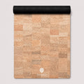A cork mat with a natural cork patchwork pattern in shades of beige, tan, and brown, featuring a black rolled edge at the top and a white ThriveLiv logo at the bottom.
