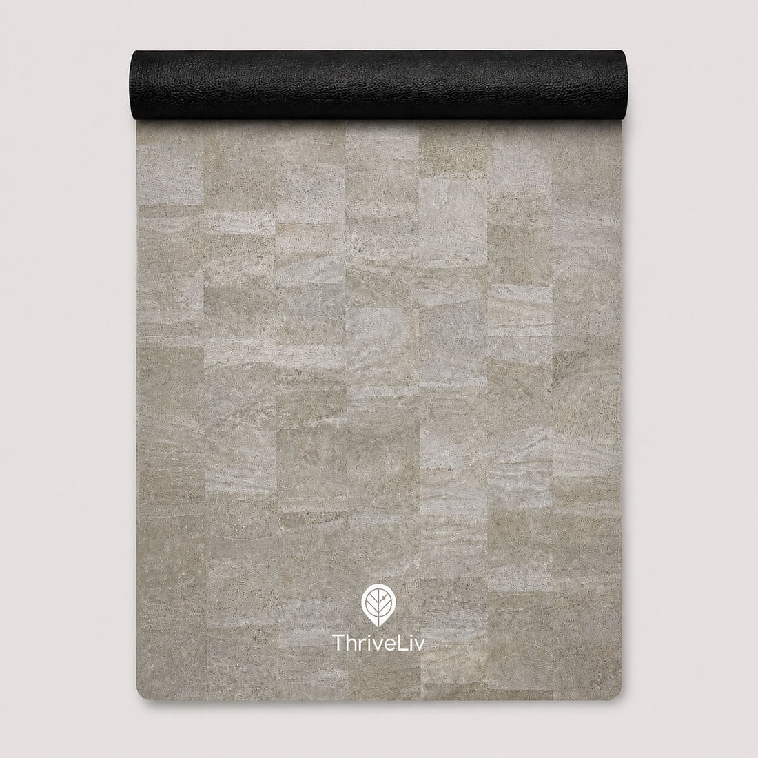 A rectangular yoga mat with a light gray stone tile pattern, partially unrolled to show its black textured underside, featuring the ThriveLiv logo at the bottom.