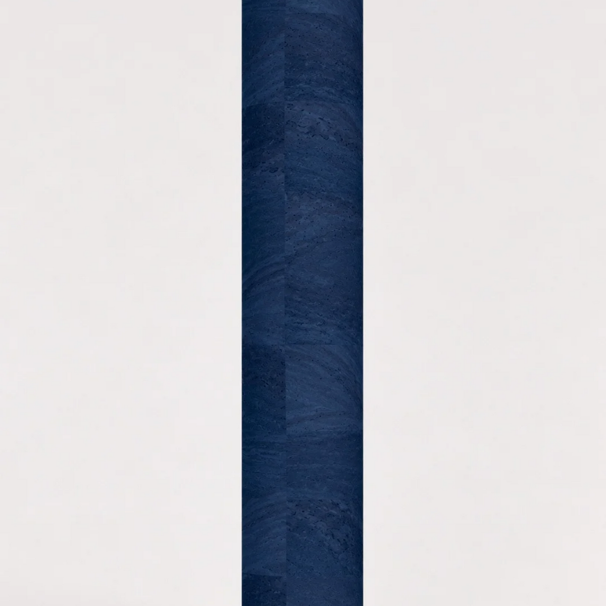 Rolled ThriveLiv natural cork yoga mat standing upright against a soft off-white studio background, showing the blue cork pattern and texture.